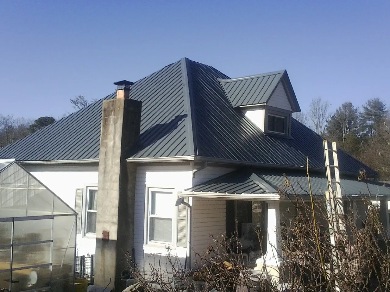 Dark blue standing seam metal roof on a white farmhouse with dormer — Slate & Tile Roof Repair by Roofing Brothers in Centerburg