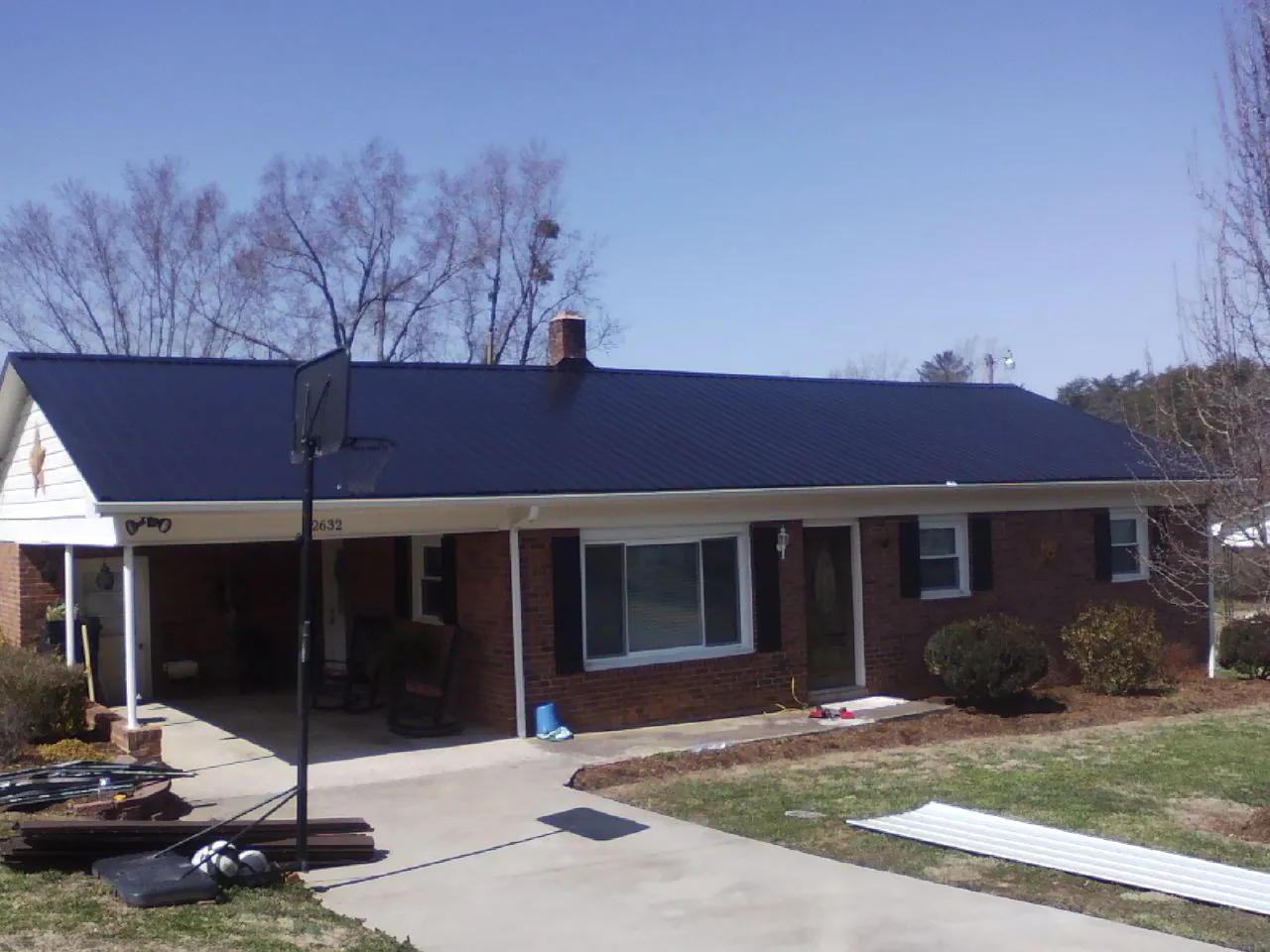 Finished dark blue metal roof on a brick ranch with a carport in Centerburg