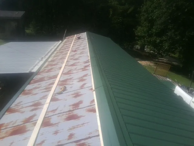 Old rusted panels beside newly installed green metal roofing — Wind Damage Roof Repair by Roofing Brothers in Centerburg