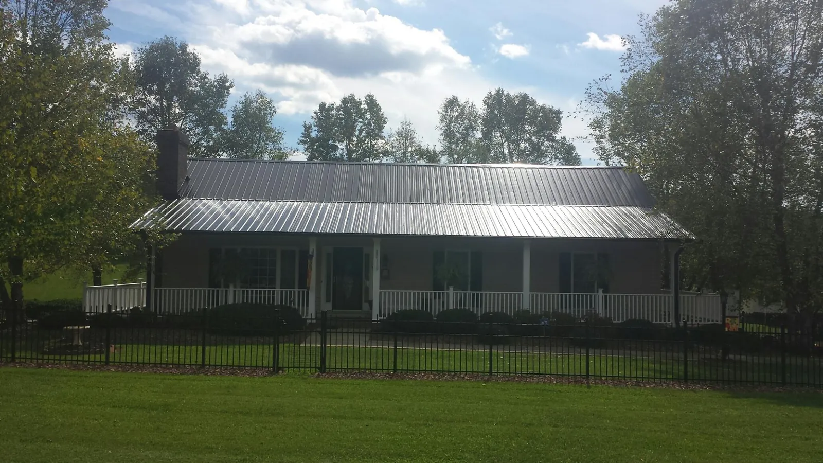 Gray metal roof on a brick ranch with a full width front porch — Gutter Guard Installation work by our crew in Centerburg