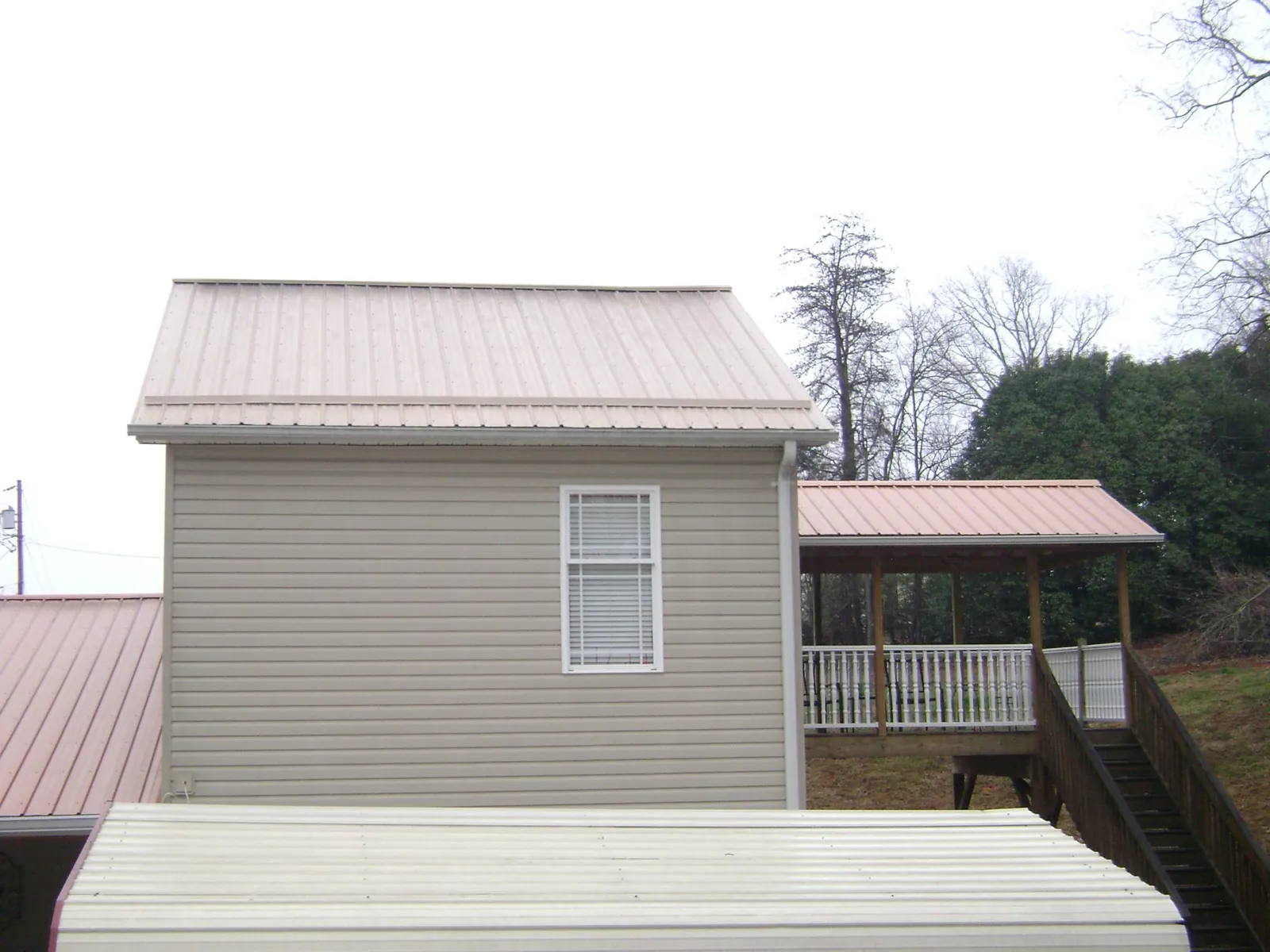 Tan metal roofs on a two story addition and attached porch, from a Roof Replacement job in Centerburg