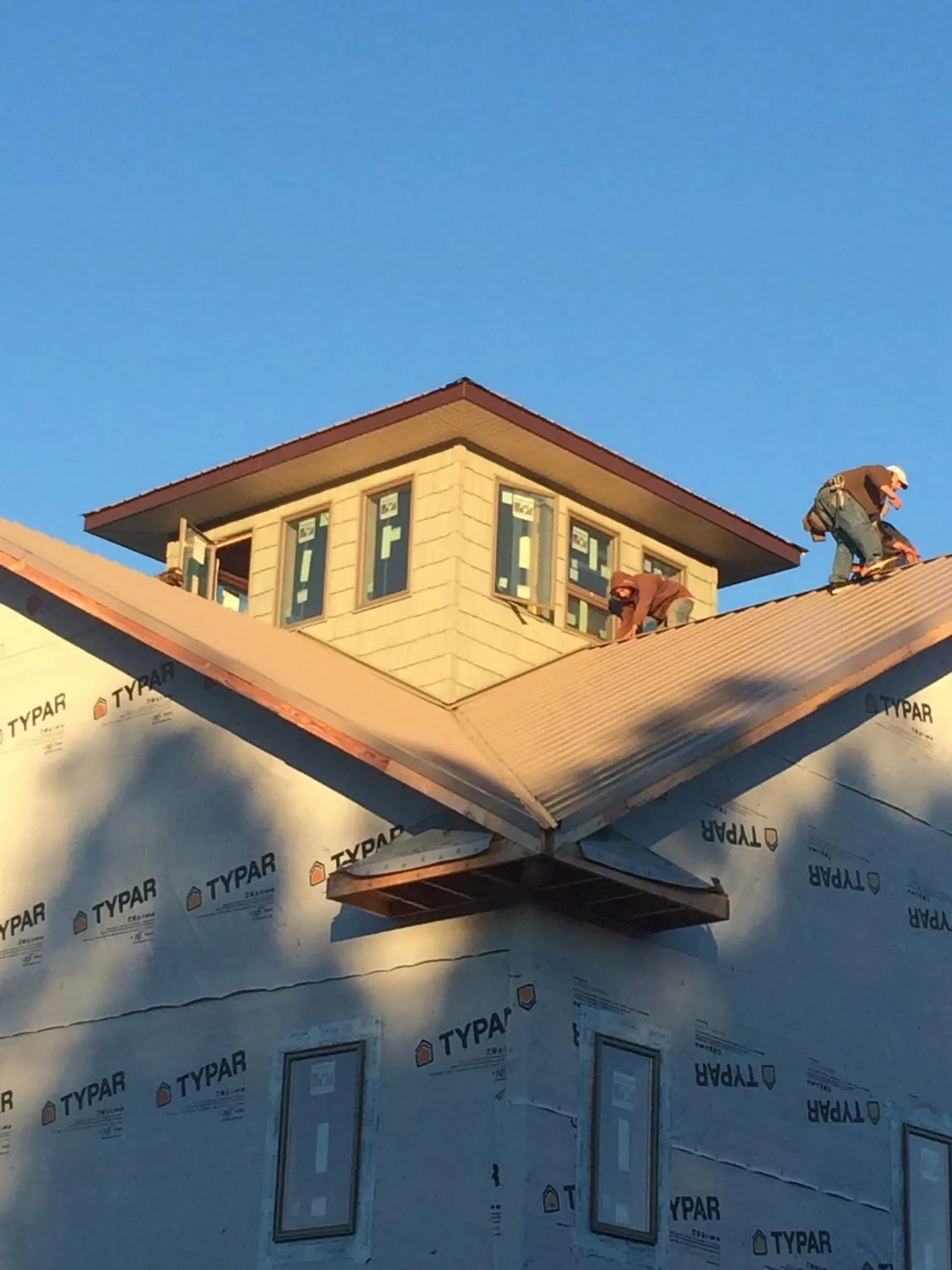 Roofers working around a rooftop cupola on a new metal roof at sunset — Roof Waterproofing in Centerburg by Roofing Brothers